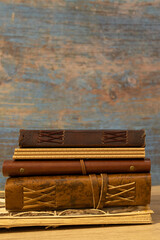 antique books and notebooks bound in leather with synthetic leather straps stacked on top of each...