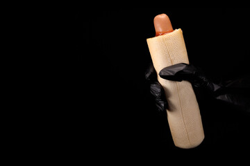 Fast food worker holding french hot dog on black background