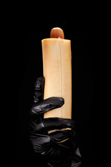 Fast food worker holding french hot dog on black background