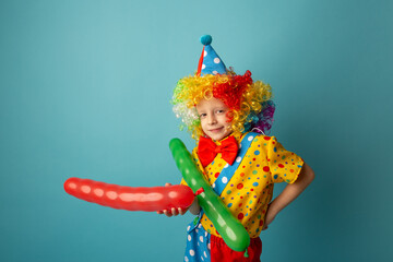 Funny kid clown against blue background. Happy child playing with festive decor. 1 April Fool's day concept