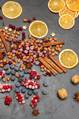 Frozen berries, spices and orange chips on the table. Black background.
