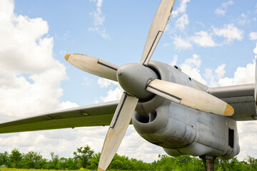 A fragment of airplane wing with four-bladed aircraft propeller against blue sky