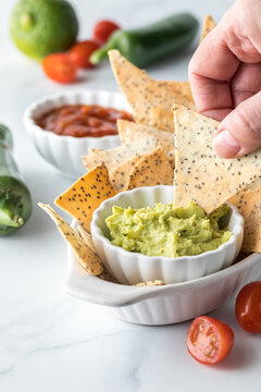 Hand Dipping A Homemade Keto Tortilla Chip Into A Bowl Of Guacamole.