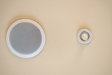 Ceiling with a speakerphone speaker and a smoke detector in an office room. The system of warning...