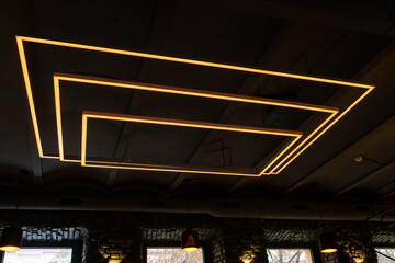 Unusual rectangular design lamps on the ceiling in an expensive restaurant. Interior design in a cafe. Lighting fixtures on the black ceiling.