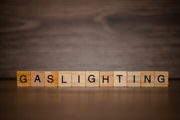 The word gaslighting composed of wooden cubes tablets on a dark wooden background
