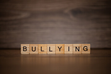 The word bullying composed of wooden cubes tablets on a dark wooden background