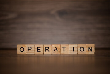 The word operation is made up of wooden cubes tablets on a dark wooden background