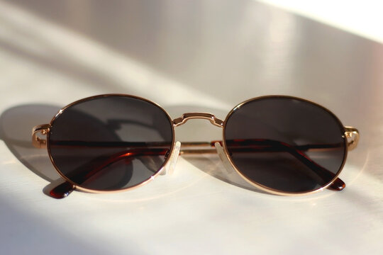 Retro round sunglasses on the table, illuminated by warm sunlight. Selective focus. - Powered by Adobe
