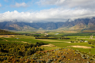 A view over Slanghoek Valley, Western Cape, in soft sunlight, showing farms and vineyards.