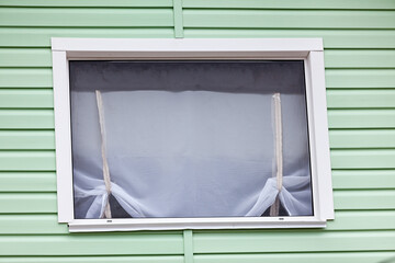 Wide plastic window with green siding exterior