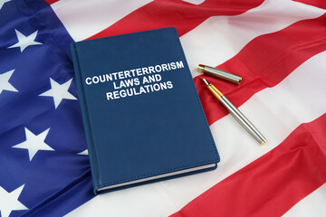 On the US flag lies a pen and a book with the inscription - COUNTERTERRORISM LAWS AND REGULATIONS