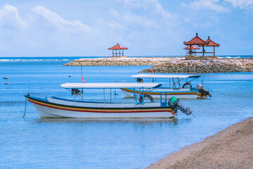 Fototapeta na wymiar Two colorful open wooden boats with roof for tourist trips at small sea bay at Sanur beach in Bali. Sanur, Indonesia