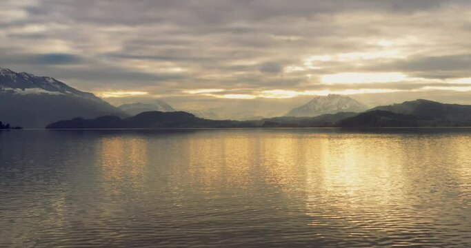 Aerial crane shot rising above a beautiful golden lake at sunset 4K