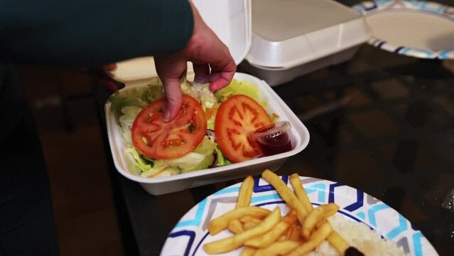 serving cole slaw and tomato to a plate with rice, French fries and rotisserie chicken
