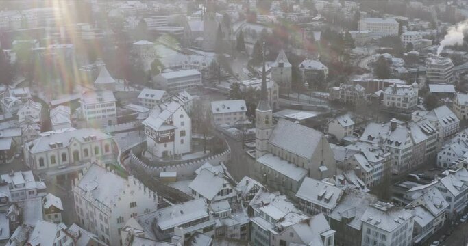 Aerial panning point of view above a snow covered old Swiss hillside town 4K