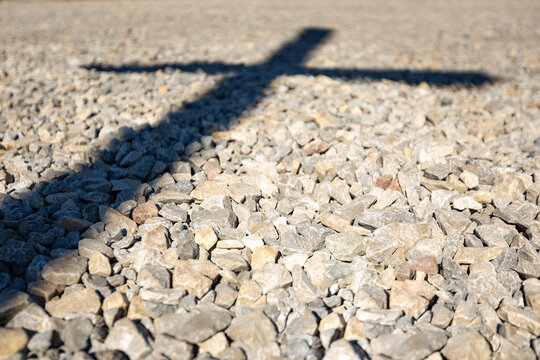 Shadow of Christian cross on rocky ground