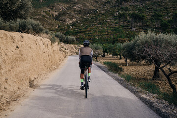 Fit cycling man is riding on gravel bike in mountains.Man riding on a gravel bike on the road. Finestrat, Alicante, Spain
