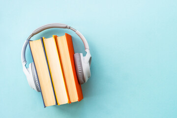 Obraz na płótnie Canvas Audio books concept. Headphones and books on blue background. Listen, study, podcast.
