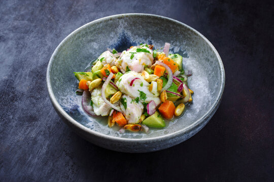 Traditional Peruvian gourmet ceviche sea bass filet piece with sweet potatoes and cancha marinated and served in lime sauce as close-up in a Nordic design bowl