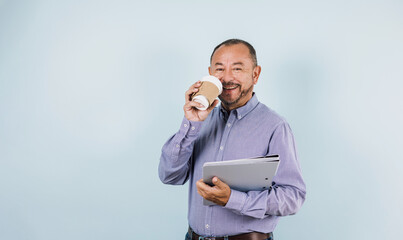 portrait of hispanic senior business man wearing casual clothes and holding a coffee and folders on blue background in Mexico Latin America	