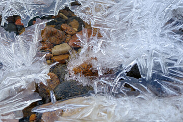 texture ice cracks, white ice crystals, winter frost background. Among the ice crystals are small pebbles