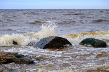The waves of the Baltic Sea wash the stones of different sizes on the shore.