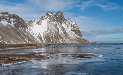 Winter landscape with snowy mountain and frozen sea in the foregound, Stokksness, Iceland
