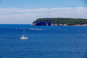 Fototapeta na wymiar sailboats compete in a sailing regatta, sailboat race, the island is in the background, sunny day, clear weather, intense blue. Adriatic Sea, Dubrovnik, Croatia