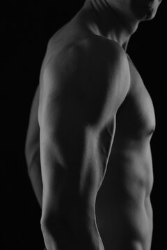 Attractive Muscular male Body. Chest , Shoulder muscles , Biceps close up. Black and White Low Key Photography