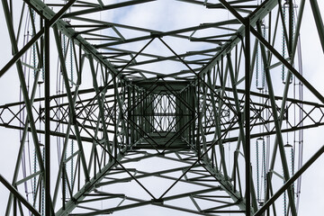 High-voltage pylon seen from the position of the person standing underneath. High voltage transmission lines