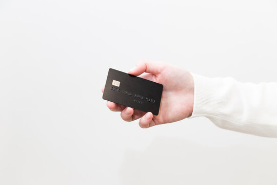 Close Up Of Female Hand Holding Black Plastic Credit Card With Chip On White Background.