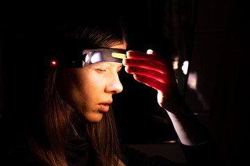 A girl with a headlamp shines in the dark, the light of a lantern on her head © Виктория Котлярчук