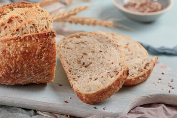 Sliced fresh baked whole grain bread with flax seeds and sesame seeds on light blue board. Bakery products