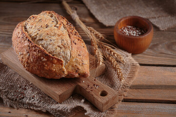 Fresh baked whole grain bread with oats, flax seeds and sesame seeds on rustic wooden board. Bakery products