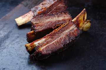 Traditional barbecue burnt chuck short beef ribs marinated with spicy rub and served with a hot chili sauce as close-up on a rustic board