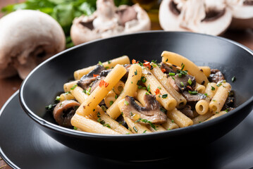 Piatto di deliziosa pasta piccante con funghi e prezzemolo, cibo italiano 