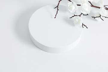 White round podium pedestal cosmetic beauty product presentation empty mockup on white background with shadows and beautiful white flowers. Flat lay cosmetic mockup