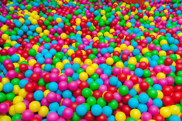 Fototapeta na wymiar Many multicolored plastic balls in a ball pool at a children's indoor playground. Recreation and entertainment concept.