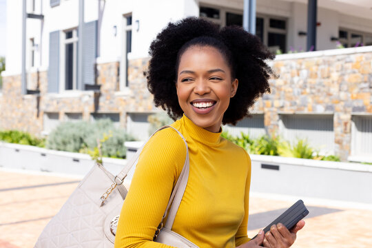 Happy african american businesswoman walking with tablet and handbag
