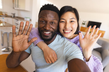 Happy diverse couple having video call and waving to camera