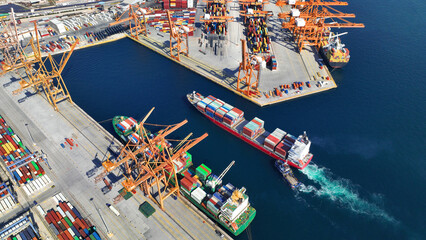 Aerial drone top down photo of container ship guided by tug boat to logistics terminal