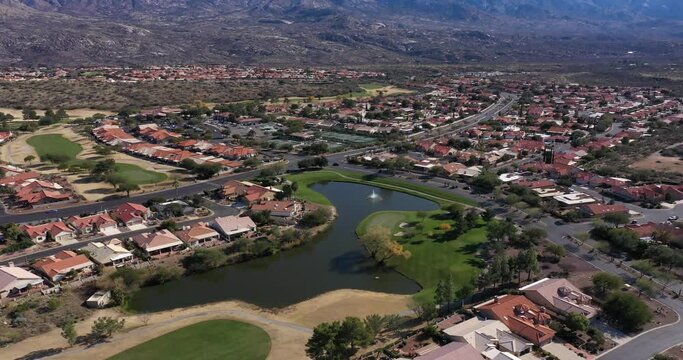 Aerial view of a suburban residential community with a golf course in a desert environment with the Catalina Mountains in the background near Tucson, Arizona.