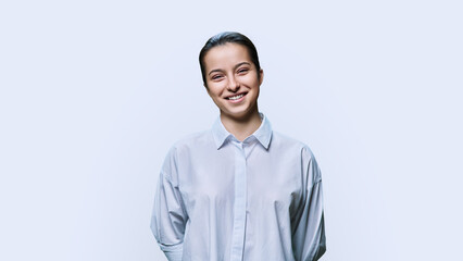 Portrait of smiling teenage girl in white shirt on light background