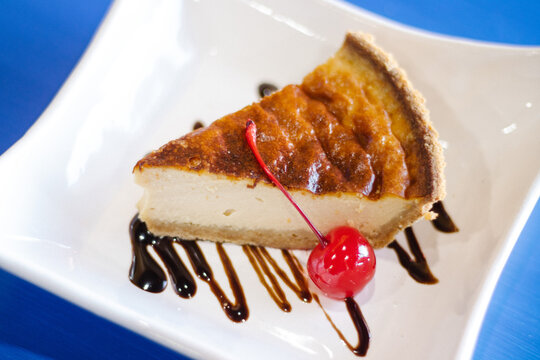 Pastel de queso con cereza sobre mesa azul 