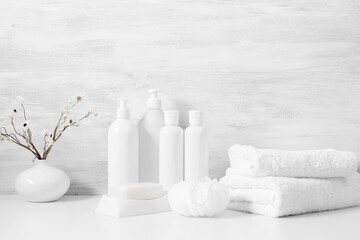 Soft light bathroom decor in white color, cosmetics product, towel, soap, dried flowers, accessories on white shelf. Elegant decor bathroom interior.
