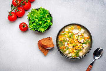 Hot vegetable soup with chicken, corn and green beans. Comfort food. Gray table background, top view