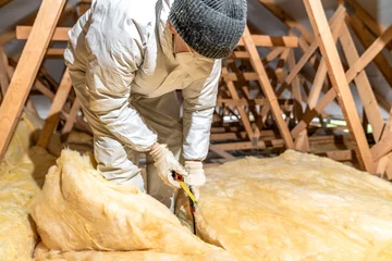 Fotobehang cutting glass wool when insulating the ceiling on the roof © edojob