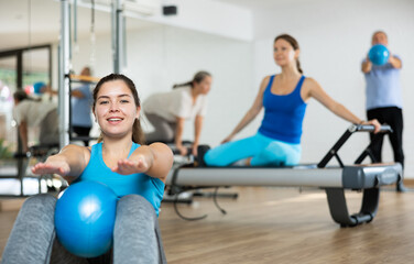 Group of young elderly people in sportswear exercising Pilates with mini balls while lying on mats...