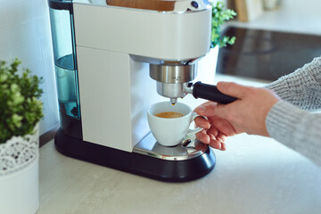 A man prepares his morning cup of coffee at home in the kitchen